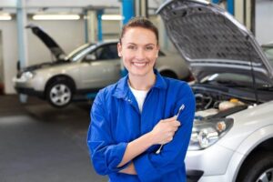 Female Mechanic smiling in front of a car with the hood open