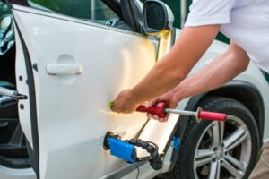 Mechanic pulling out dent on a car door