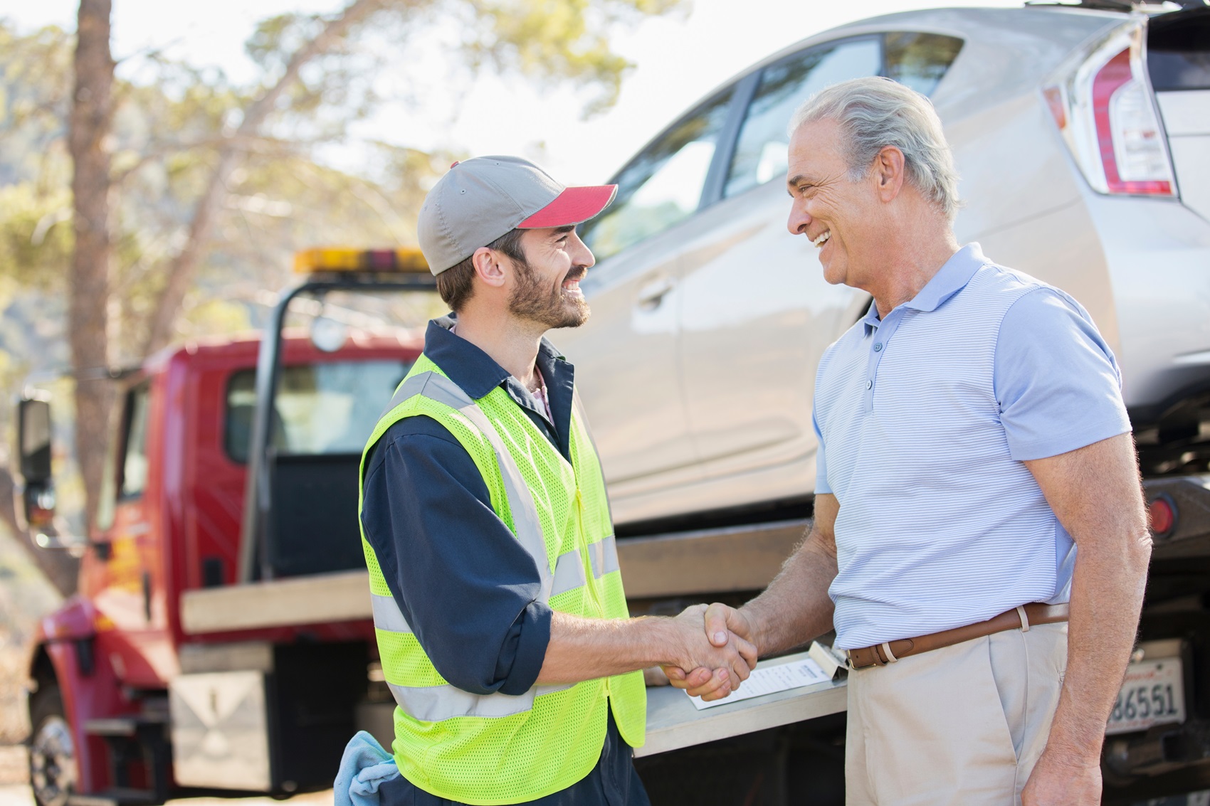 tow truck driver shaking hands with owner of vehicle