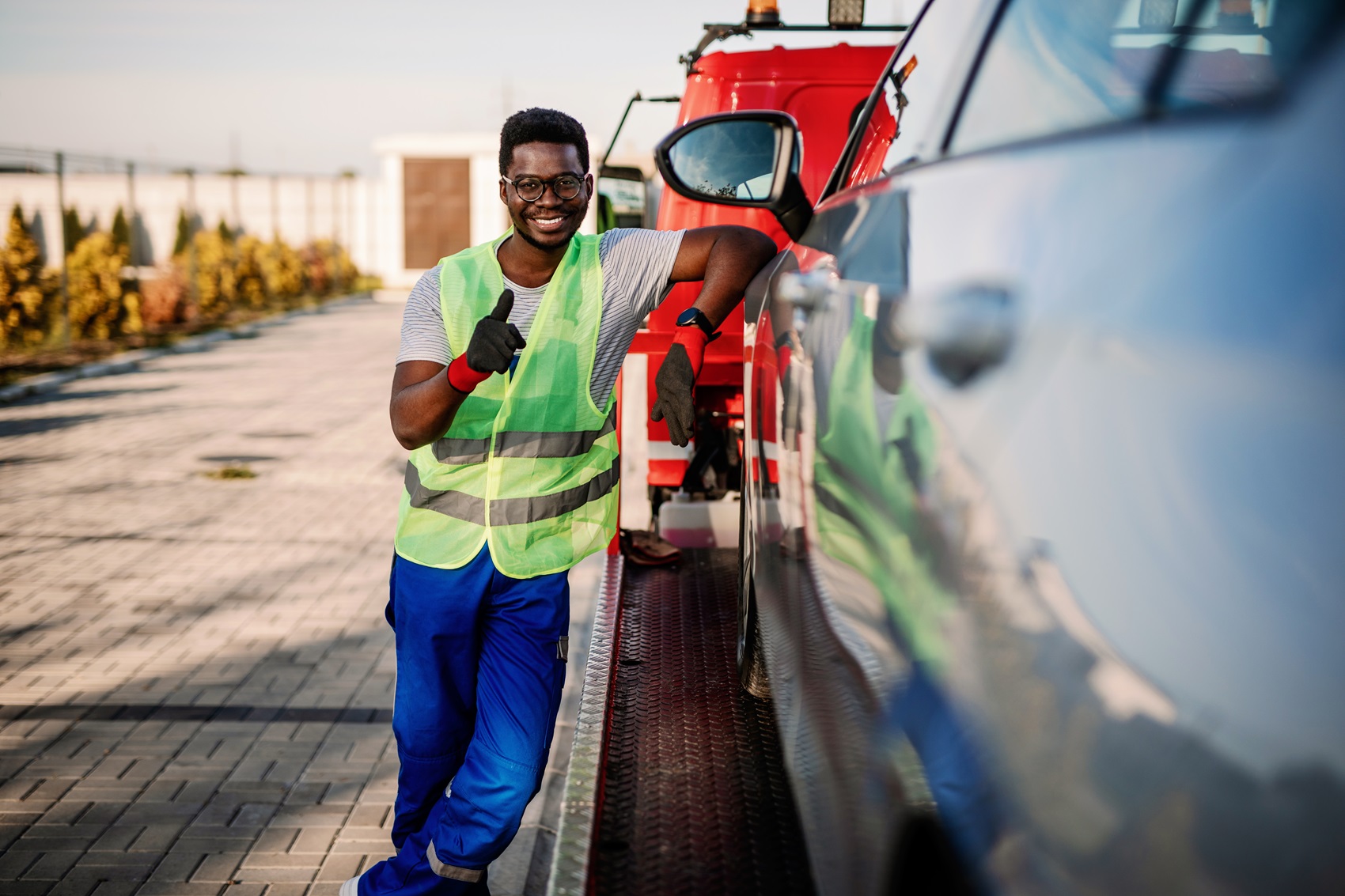tow truck driver leaning against vehicle with thumbs up