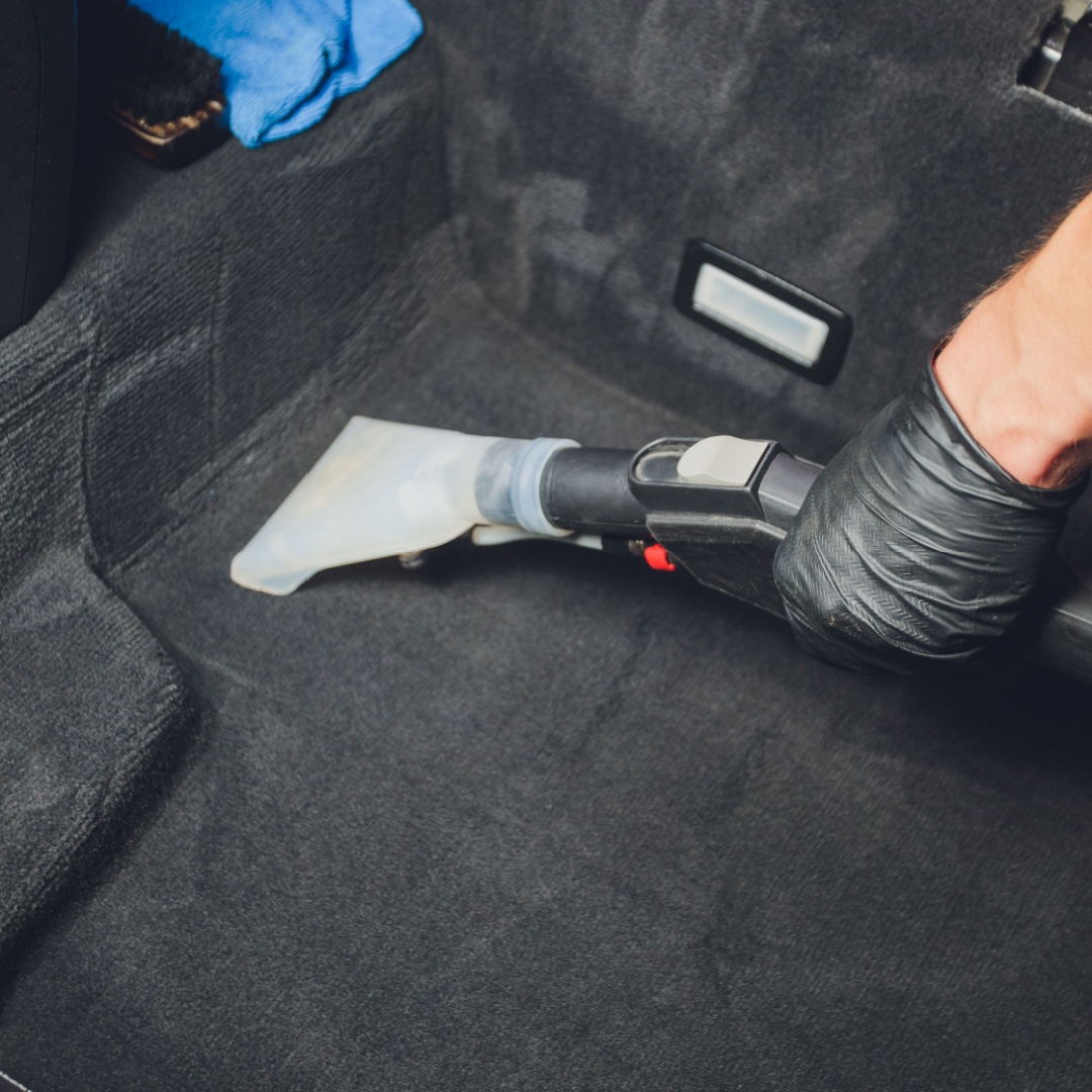 Detailer vacuuming interior of vehicle
